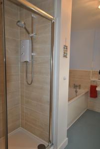 The Neuk- contemporary coastal apartment في أنستروذر: دش في حمام مع حوض استحمام ودش