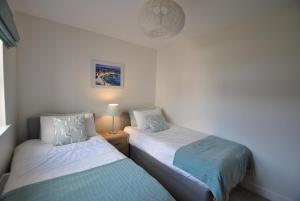The Neuk- contemporary coastal apartment في أنستروذر: سريرين في غرفة صغيرة بجدران بيضاء