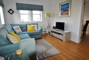 a living room with a blue couch and a television at The Neuk- contemporary coastal apartment in Anstruther