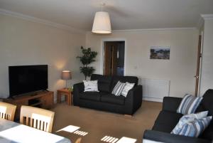 a living room with a couch and a tv at Forth View- stylish upper apartment with sea views in Anstruther