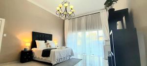 a bedroom with a bed with a chandelier and a window at The Dream Guesthouse in Ermelo