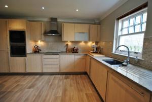 a kitchen with wooden cabinets and a sink and a window at Darnley View- spacious countryside retreat in Crail