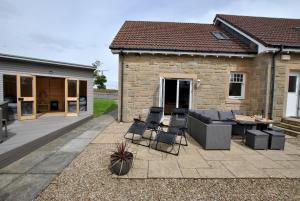 a patio with chairs and a table and a building at Darnley View- spacious countryside retreat in Crail