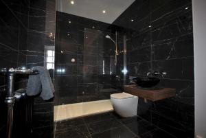 a black tiled bathroom with a toilet and a sink at Seaspray- harbourfront home in idyllic location in Pittenweem