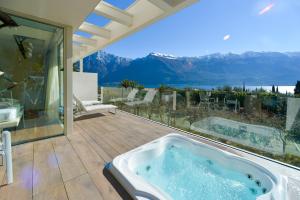 un patio con bañera de hidromasaje y vistas a las montañas en Park Hotel Imperial, en Limone sul Garda