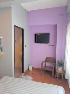 a bedroom with purple walls and a tv on the wall at Chiang mai Walking Street Home ( เชียงใหม่วอล์คกิ้งสตรีทโฮม ) in Chiang Mai