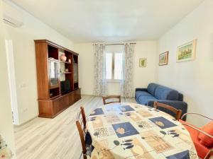 a living room with a table and a blue couch at Trilocale Jolly in Marina di Bibbona