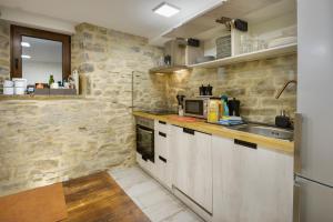 a kitchen with white cabinets and a stone wall at Casa Campanilla Jaca in Jaca