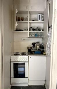 a small kitchen with a white stove and cabinets at Studio The Vibe / 25min to airpt & 5min to center in Helsinki