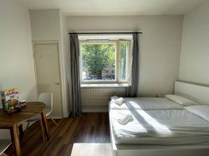 a bedroom with a bed and a table and a window at Studio The Vibe / 25min to airpt & 5min to center in Helsinki