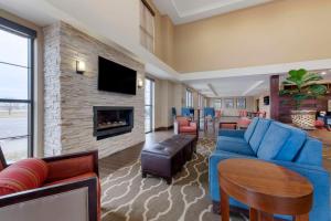 Una sala de estar con un sofá azul y una chimenea. en Comfort Suites & Conference Center, en Worthington