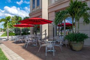 a group of tables and chairs with red umbrellas at Wyvern Hotel, Ascend Hotel Collection in Punta Gorda