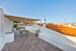 un balcón blanco con mesa y sillas en la azotea en Casa Helena, en Ferragudo