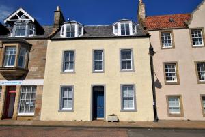 a large brick building with white windows and a blue door at Market Apartment- harbourfront studio Pittenweem in Pittenweem