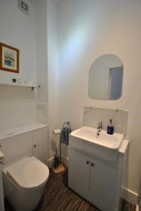 La salle de bains blanche est pourvue de toilettes et d'un lavabo. dans l'établissement Gyles Apartment - harbourfront studio Pittenweem, à Pittenweem