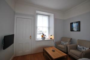 a living room with a table and a window at Gyles Apartment - harbourfront studio Pittenweem in Pittenweem