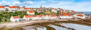a group of houses on a hill next to the ocean at Craws Nest Cottage- stylish traditional home in Pittenweem