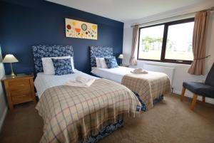 a bedroom with two beds and a chair and a window at Kittle View near Anstruther in Carnbee