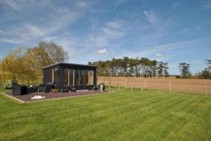 a small black building in a field with a grass field at Kittle View near Anstruther in Carnbee