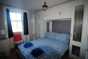 a bedroom with a bed with blue sheets and a window at Harbourside- home by the sea in coastal village in Saint Monance