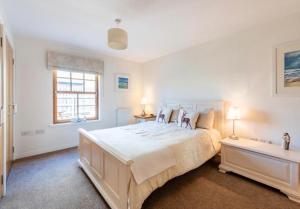 a white bedroom with a large bed and two lamps at Coastal Haven- stunning home in Crail in Crail