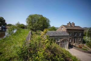 an old house on a hill next to a river at Stunning stone coach house in Marple