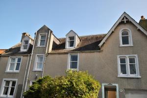 an old house with white windows and a tree at Mariners Retreat- spacious apartment in Crail in Crail
