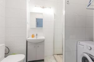 a white bathroom with a sink and a washing machine at Central Apartments Silver L1F/21 in Gdańsk