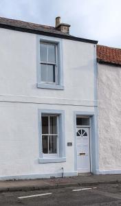 a white house with two windows and a door at Sea Whisper- lovely home in charming village in Pittenweem