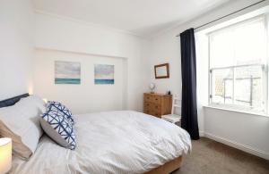 a white bedroom with a bed and a window at Sea Whisper- lovely home in charming village in Pittenweem