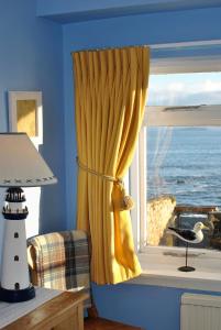 a window with a yellow curtain and a bird on a window sill at Catherine Cottage seaside home in Anstruther