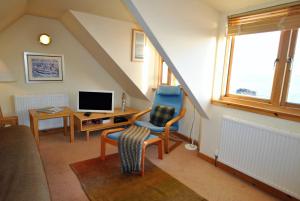 a living room with a staircase with a chair and a television at Catherine Cottage seaside home in Anstruther +17 photos