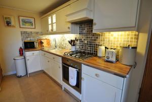 a kitchen with white cabinets and a stove top oven at Catherine Cottage seaside home in Anstruther