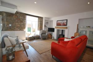 a living room with red furniture and a stone wall at Puffin House- stylish home by the sea in Anstruther