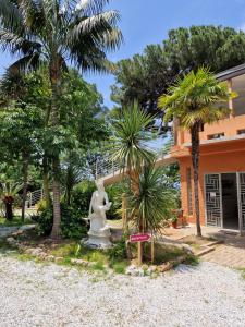 a statue in front of a building with palm trees at Hotel - Giardino Marchese D'Altavilla in Tropea