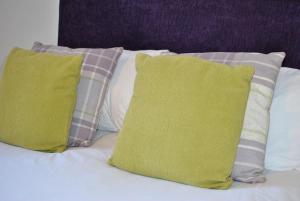 1 cama con 3 almohadas y 2 almohadas verdes en Calabeinn, en Anstruther