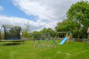 two swings and a swing set in a yard at East Green Farm Cottages - The Granary in Saxmundham