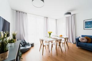 Apartament Hallera - 70m - 3 Pokoje - Winda - Garaż - Nowe Osiedle في فروتسواف: غرفة معيشة مع طاولة وكراسي بيضاء