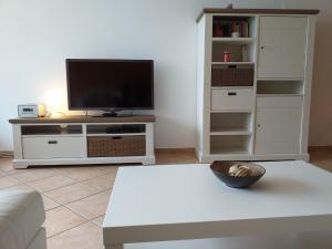 un soggiorno con TV e un centro di intrattenimento bianco di Ferienwohnung 211 a Timmendorfer Strand