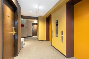 a corridor of a bathroom with yellow walls at Hotel Sanrriott Osaka Hommachi in Osaka