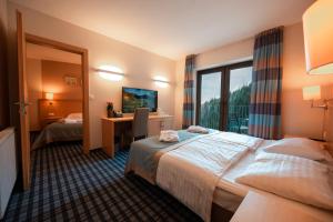 een hotelkamer met een bed, een bureau en een raam bij Wellness Hotel Montis in Mozirje