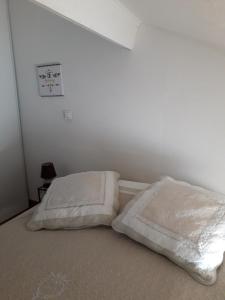 Una cama con dos almohadas blancas encima. en La P'tite Maison, en Lisle