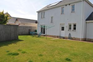 a yard with a white house and a fence at Faolin- superb detached family villa East Neuk in Anstruther