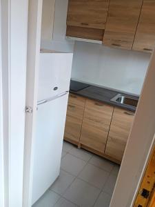 een keuken met een witte koelkast en houten kasten bij Apartamento en Cala de Finestrat - Edificio Atalaya 5º 10 in Cala de Finestrat