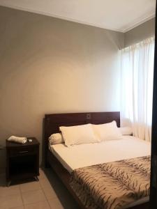 a bedroom with a bed with a night stand and a window at Womy Homy in Bogor