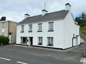 a white house with a red door on a street at Mary's of Mulranny in Mulranny