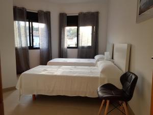 - une chambre avec deux lits et une chaise noire dans l'établissement Sunny apartment great for Cycling, 300mb wifi, à Xaló