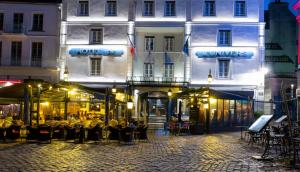 una calle con mesas y sillas frente a un edificio en Hotel De L'univers en Saint-Malo