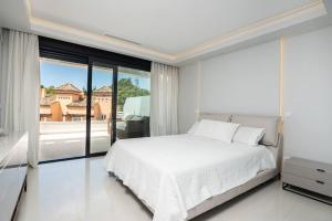 a bedroom with a white bed and a large window at Puente Romano Luxury Villa in Marbella +67 photos