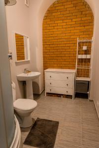 een badkamer met een wastafel, een toilet en een bakstenen muur bij Studio type apartment in Ķegums in Ķegums